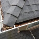 Clogged roof gutters filled with tree leaves and pine needles
